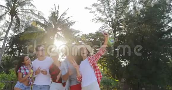 人组拍摄手机智能手机图片热带棕榈树上的快乐男女视频的预览图