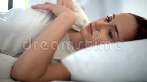 沮丧的成年妇女在床上铺上毯子视频的预览图