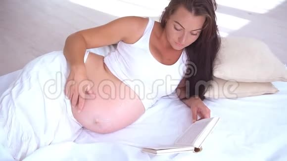 孕妇躺在床上看书分娩视频的预览图