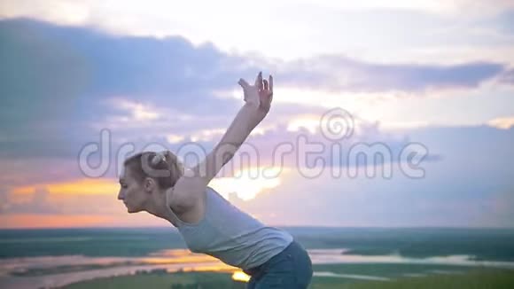 日落时在夏日草地上表演跳跃的年轻女子视频的预览图