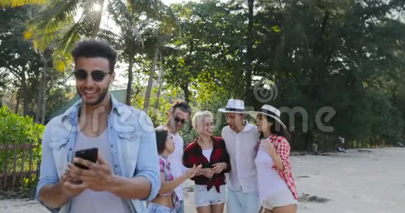 利用手机打电话的拉丁人在热带棕榈树公园聊天视频的预览图