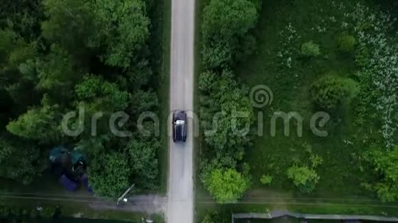 村里的路汽车沿着树和房子之间的道路行驶视频的预览图