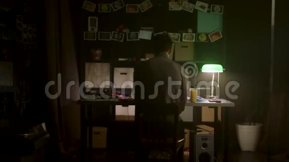 在光线昏暗的房间里一个人坐在黑板前的桌子旁写着项目笔记股票人是视频的预览图
