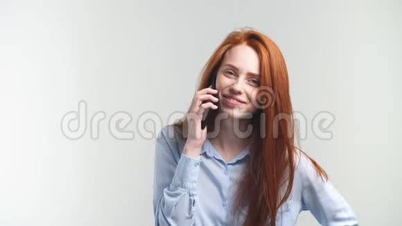 年轻迷人的红发女郎用电话和朋友聊天和微笑视频的预览图