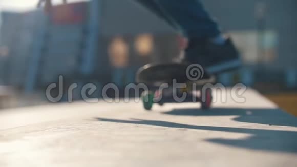 在阳光明媚的日子里滑板运动员的腿在斜坡上滑动视频的预览图