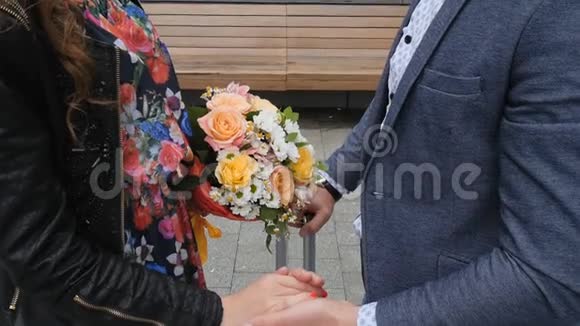 一对相爱的情侣在浪漫的约会中的手背景是一束美丽的花束视频的预览图
