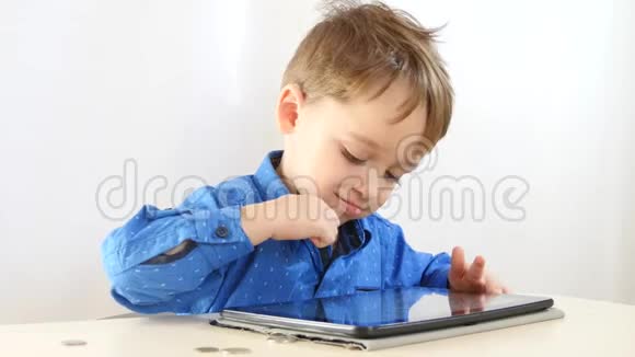 小男孩正在玩平板电脑桌上有一杯茶互联网和无线技术这个视频的预览图