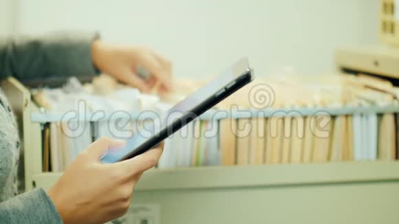 那个女人在档案里工作翻阅抽屉里的条目使用平板电脑视频的预览图