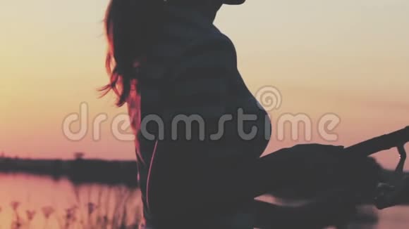 一个年轻女子的剪影手里拿着一根盘旋的钓竿拂晓时把钓上来的鱼卷起来视频的预览图