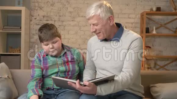 老人正在教一个年轻的胖子祖父和孙子幸福的家庭家庭舒适的概念60英尺视频的预览图