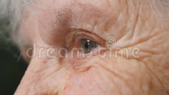 特写老妇人抬头的肖像一位有皱纹的老太太的眼睛侧视视频的预览图