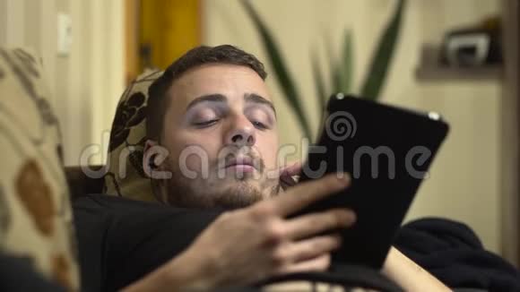 一个男人用平板电脑在床上睡着的中弹视频的预览图