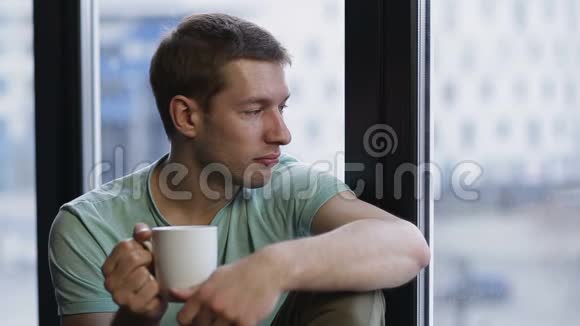 放松的年轻人在窗户附近喝咖啡视频的预览图