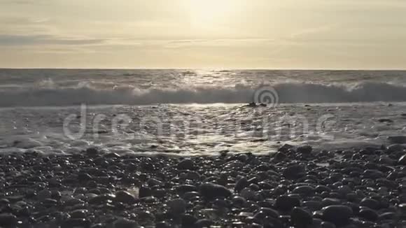 强大的海浪在阳光下冲刷海滩上的卵石滩视频的预览图