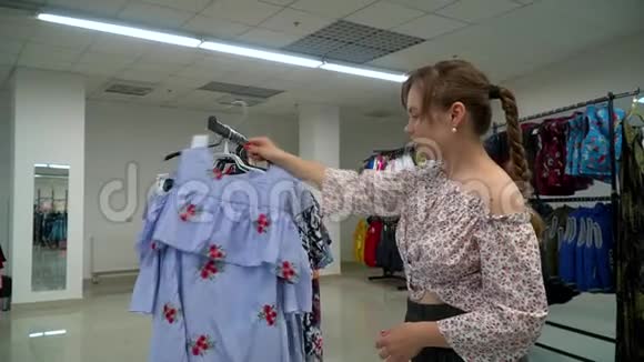 漂亮的女人在商店里选了一件衣服购物女孩视频的预览图