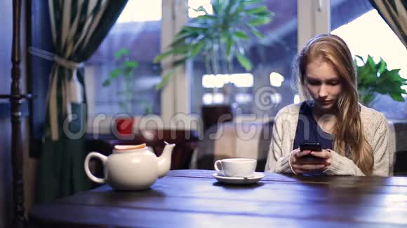 咖啡馆里可爱的女孩在智能手机上打字视频的预览图