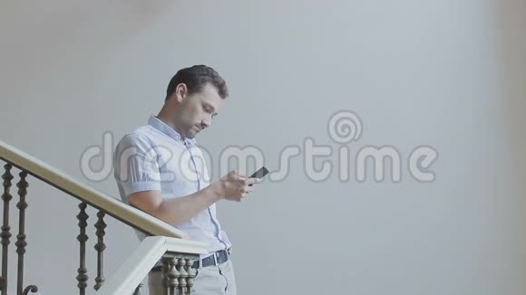 微笑的人正拿着电话站在楼梯上视频的预览图