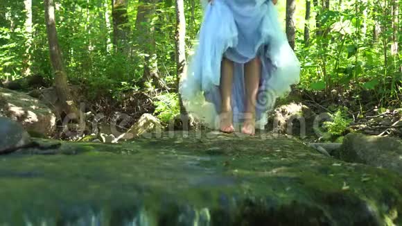 行走的女孩在野生丛林森林里旅行穿着一件连衣裙踏着干净的山河视频的预览图