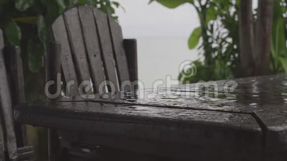 海滩附近的户外咖啡馆里的一张桌子和椅子上下着小雨视频的预览图
