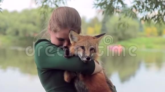 漂亮的雌性手牵狐狸在户外与野生动物合影视频的预览图