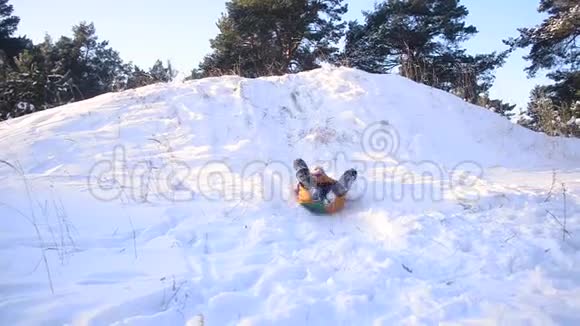 快乐的少女在白雪覆盖的森林背景下的冬天公园里带着雪滚下山一家人在一个温暖的小屋里视频的预览图