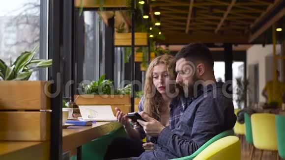 一个男人和一个女孩在咖啡馆里用平板电脑讨论他们的创业视频的预览图