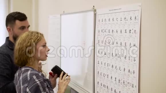 一对年轻男女在教室里一起研究象形文字视频的预览图