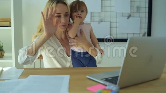 美丽的母亲抱着一个婴儿挥舞着手视频的预览图