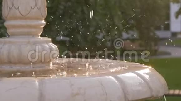 日落时分在城市公园的白色大理石喷泉中溅起水花视频的预览图