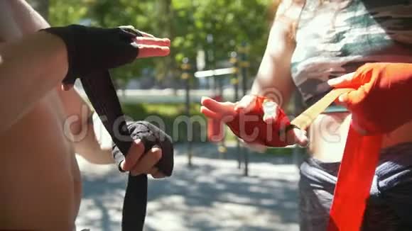 运动型高加索人男子和女子用绷带包扎双手在夏季公园进行训练动作缓慢视频的预览图