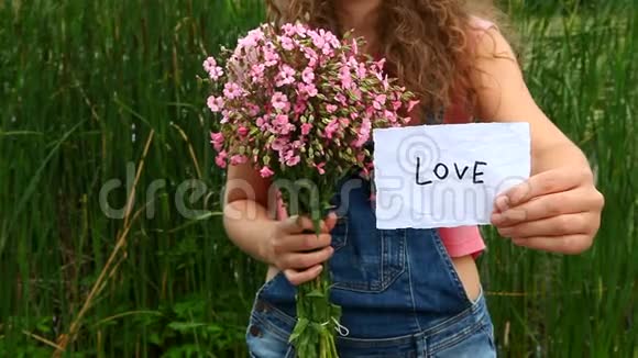 年轻女子展示爱情和粉红色的花朵视频的预览图