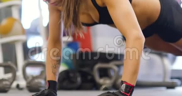 健身操垫上做俯卧撑的训练有素的妇女的特写视频的预览图