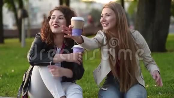两个年轻漂亮的女人在户外聊天喝咖啡视频的预览图