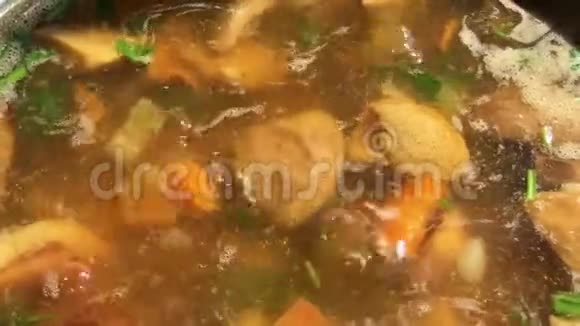 蘑菇汤配香菜牛肝菌和蔬菜煮锅中用勺子煮和搅拌视频的预览图
