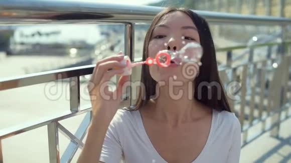漂亮的亚洲女孩站在桥上吹泡泡视频的预览图