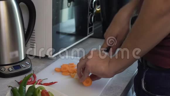 男人轻轻而仔细地切胡萝卜做沙拉以取悦心爱的慢动作的人视频的预览图