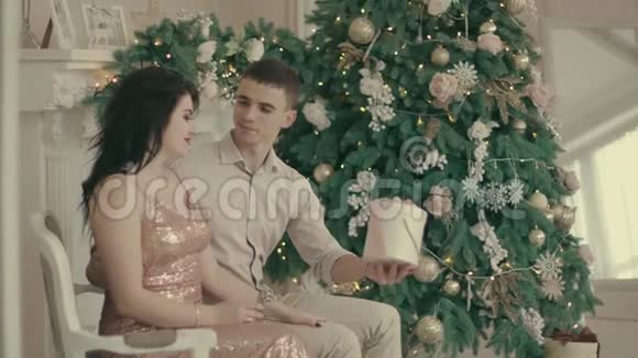 年轻的情侣在装饰着圣诞树的舒适圣诞房里相爱视频的预览图