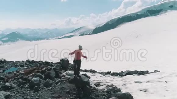 在雪山上的岩石上翩翩起舞的鸟瞰美景视频的预览图