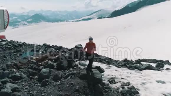 在雪山上的石头上翩翩起舞的鸟瞰美景视频的预览图
