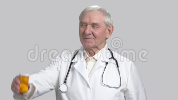 微笑的老资深医生与药丸罐和拇指向上视频的预览图