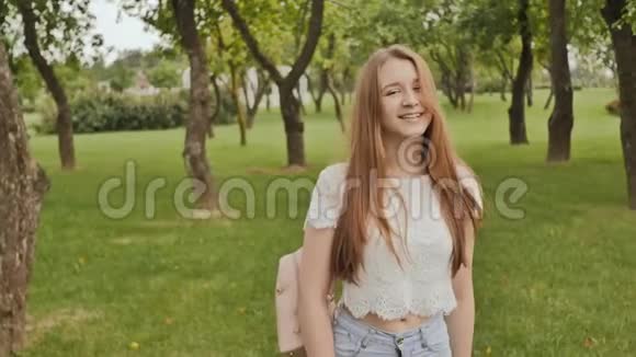 年轻漂亮的女学生留着长发背着一个背包在公园里散步在学习期间休息视频的预览图