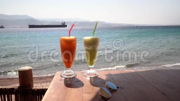 两杯鸡尾酒在沙滩上的新鲜咖啡桌上视频的预览图