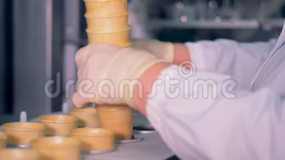 一个工厂工人正在把一堆华夫饼杯子插入传送带视频的预览图