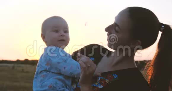 快乐的年轻母亲在太阳落山时在田野里和孩子玩耍视频的预览图
