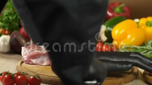 戴着黑手套的厨师把一块生肉和大蒜结合在一起这些肉用刀子迷迭香和视频的预览图