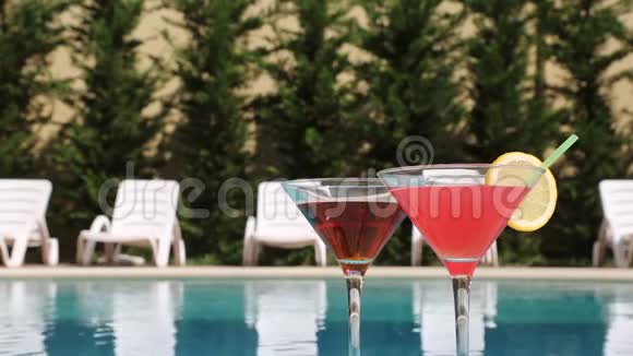 在游泳池附近的夏季炎热中两杯盛满了夏季饮品视频的预览图