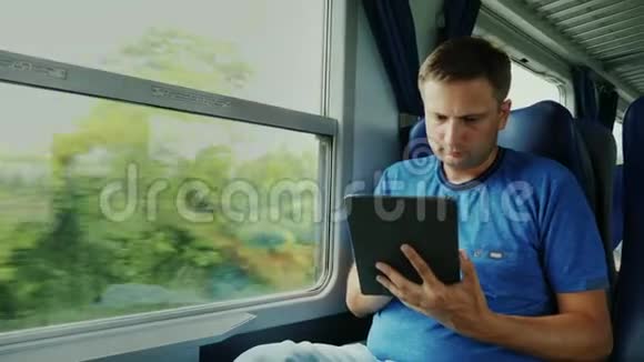 一个人在火车上旅行靠窗的位置使用数字平板电脑道路上的装置视频的预览图