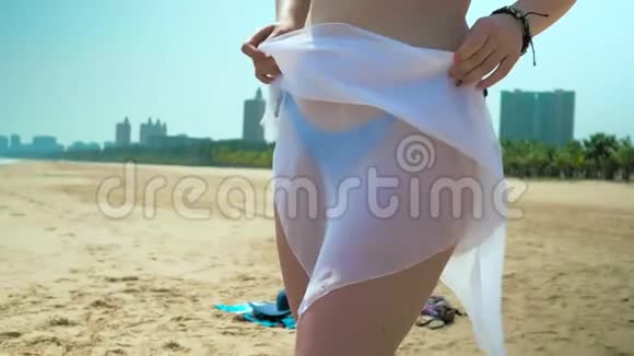 海滩上的年轻女孩在臀部穿白色透明织物中弹慢动作视频的预览图
