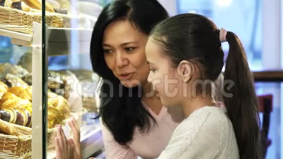 母亲和女儿在面包店购物在橱窗里挑选糕点视频的预览图