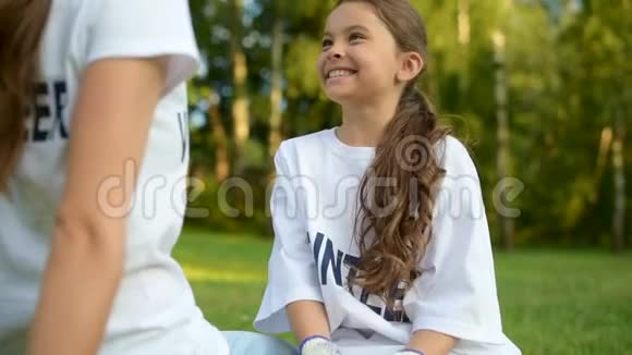 坐在草地上和志愿者交谈的活泼的女孩视频的预览图